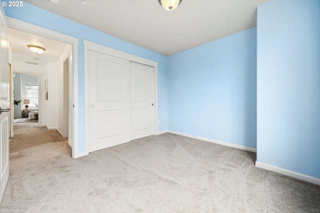 unfurnished bedroom featuring carpet flooring, baseboards, and a closet