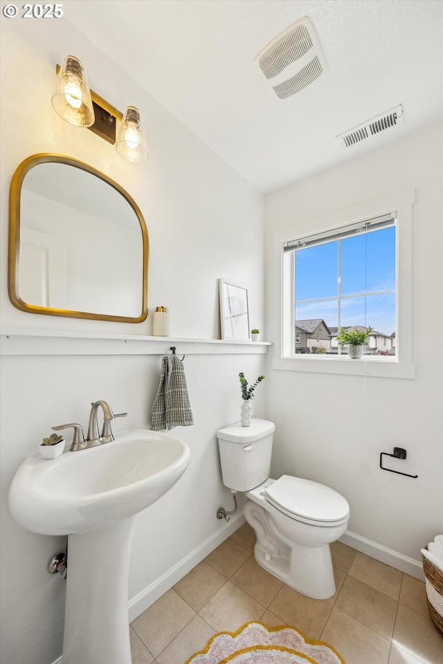 half bath featuring toilet, baseboards, and tile patterned floors