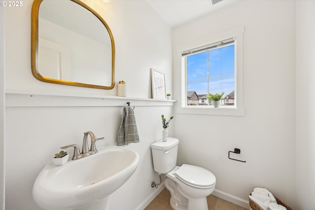 half bath featuring a sink, baseboards, toilet, and tile patterned floors