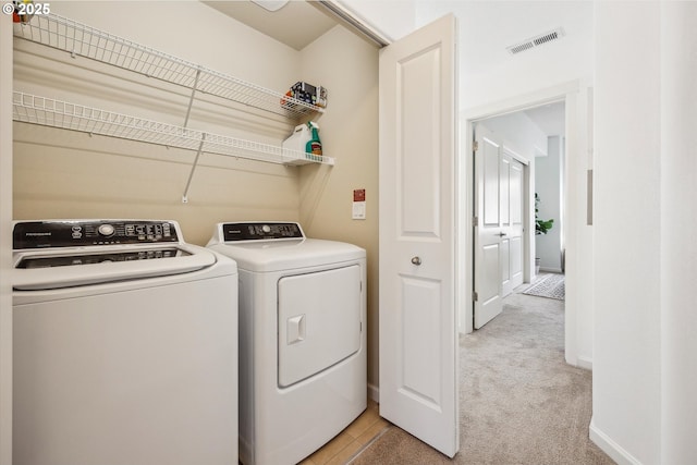 clothes washing area featuring washer and clothes dryer, light colored carpet, and baseboards