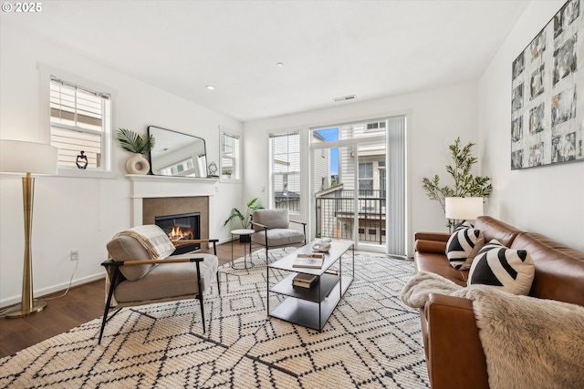 living area featuring wood finished floors, a glass covered fireplace, and baseboards