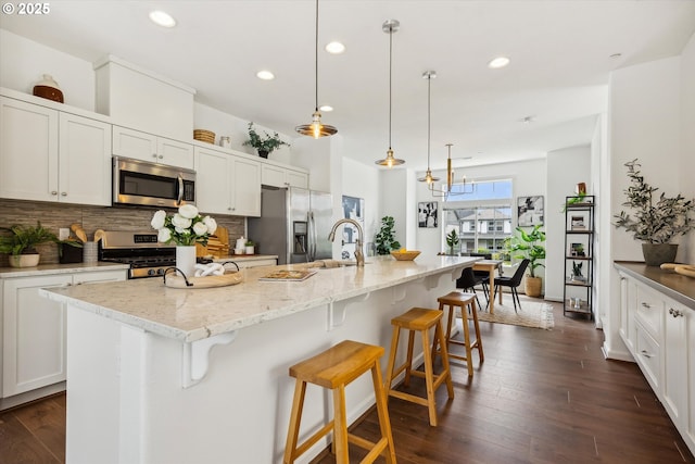 kitchen with appliances with stainless steel finishes, decorative backsplash, recessed lighting, a breakfast bar area, and a spacious island