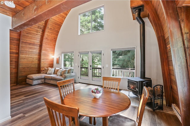 10056 Beach Dr, Birkenfeld, OR 97016 - dining room featuring a wood stove, wooden ceiling with exposed beams, a baseboard radiator, high vaulted ceiling, and wood finished floors
