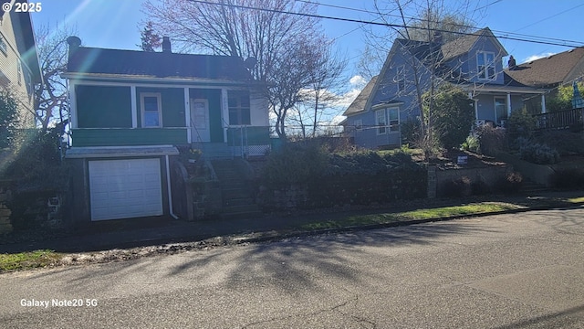 view of front of house featuring stairs, covered porch, and an attached garage