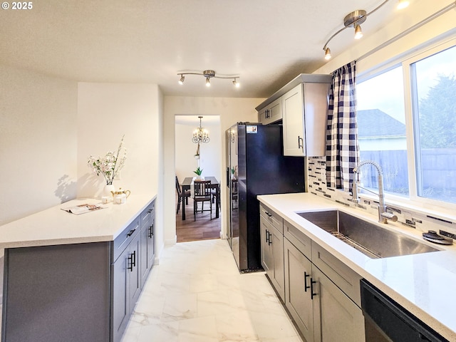 kitchen with hanging light fixtures, sink, backsplash, gray cabinets, and dishwasher