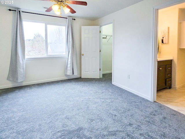 unfurnished bedroom with connected bathroom, carpet, a walk in closet, and ceiling fan