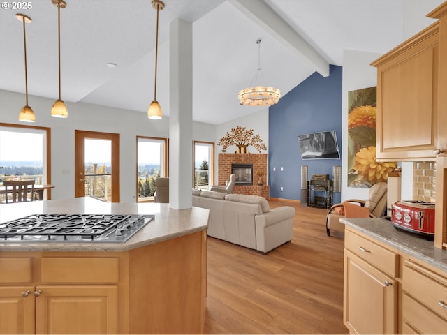 kitchen with vaulted ceiling with beams, light wood finished floors, stainless steel gas cooktop, and light brown cabinetry