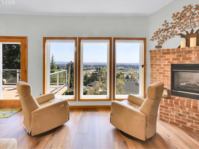 sitting room featuring a brick fireplace and hardwood / wood-style flooring