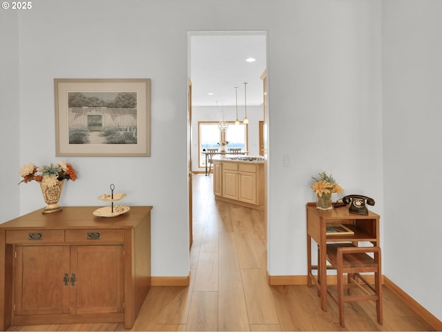 hallway featuring baseboards, recessed lighting, and light wood finished floors