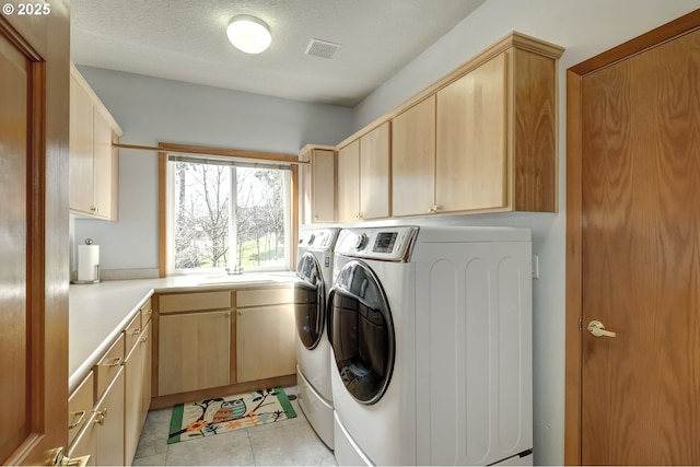 laundry area with visible vents, independent washer and dryer, a sink, cabinet space, and light tile patterned flooring