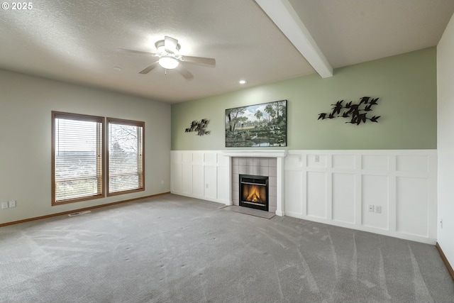 unfurnished living room featuring visible vents, beam ceiling, a ceiling fan, carpet flooring, and a tile fireplace