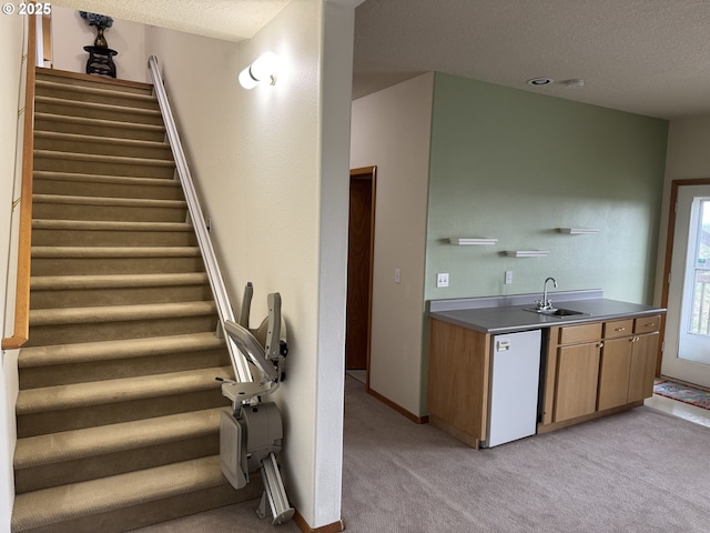 staircase featuring carpet, baseboards, and a textured ceiling