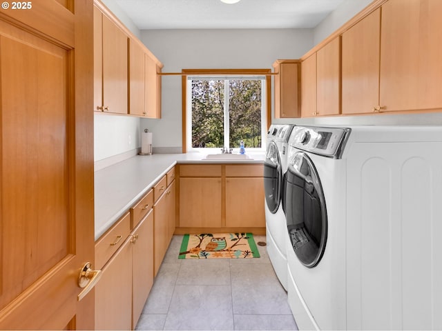 laundry area featuring a sink, cabinet space, light tile patterned floors, and washing machine and dryer