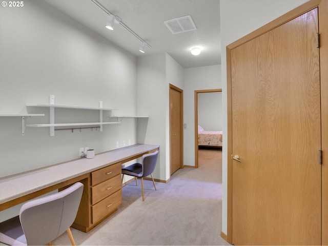 home office featuring track lighting, light carpet, built in study area, baseboards, and visible vents