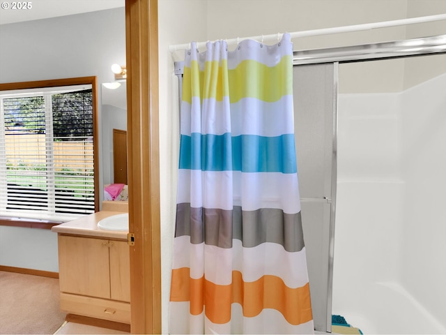bathroom with baseboards, a shower stall, and vanity