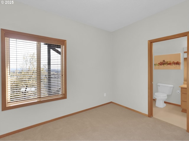 unfurnished bedroom with baseboards, multiple windows, ensuite bathroom, and light colored carpet