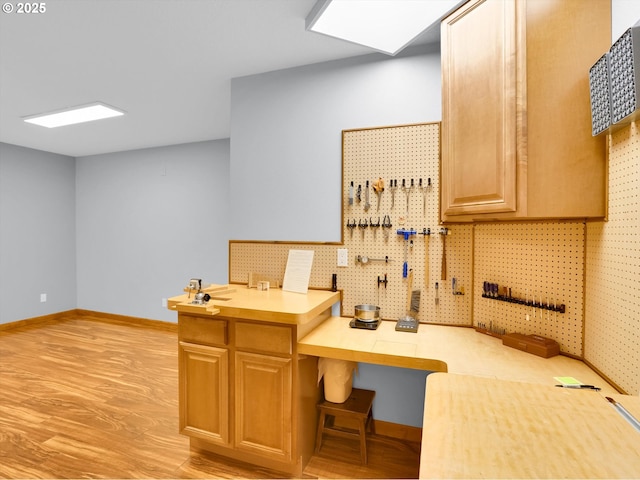 interior space with baseboards, light countertops, and light wood finished floors