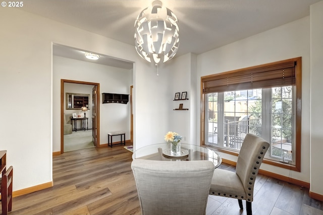 dining space featuring baseboards, a notable chandelier, and light wood finished floors