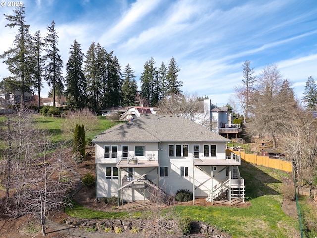 rear view of house with a balcony, stairway, fence, and a lawn