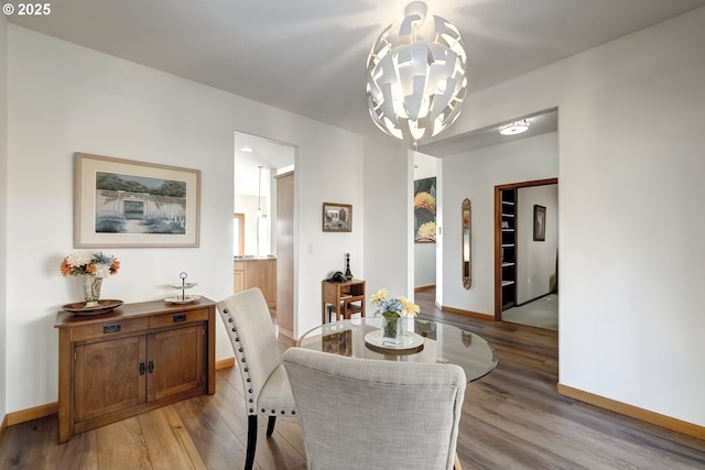 dining space with baseboards, a chandelier, and light wood finished floors