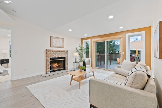 living room with light wood finished floors, recessed lighting, a brick fireplace, and baseboards