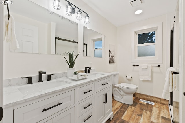 full bathroom with a sink, visible vents, toilet, and wood finished floors