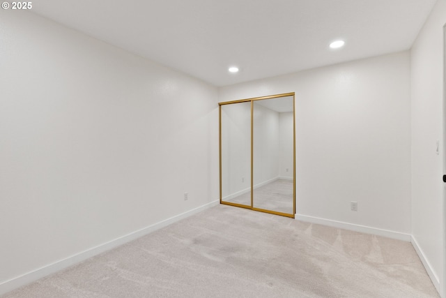 unfurnished bedroom with recessed lighting, light colored carpet, baseboards, and a closet