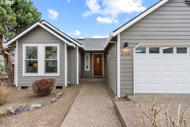 entrance to property featuring a shingled roof and a garage