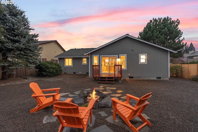 back of house at dusk with crawl space, a shingled roof, a fire pit, and fence