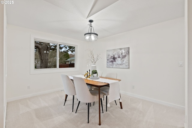 dining area with baseboards and light colored carpet