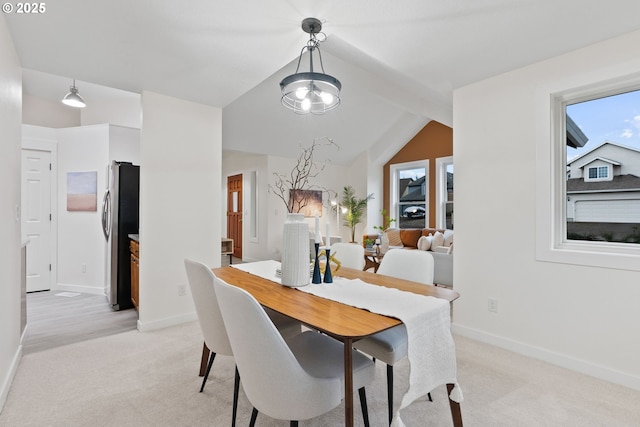 dining space featuring baseboards, light carpet, and lofted ceiling