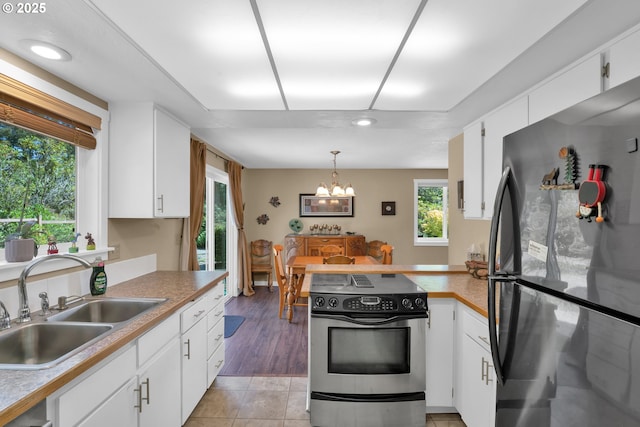 1588 20th St, Florence, OR 97439 - kitchen with appliances with stainless steel finishes, white cabinets, a chandelier, a peninsula, and recessed lighting