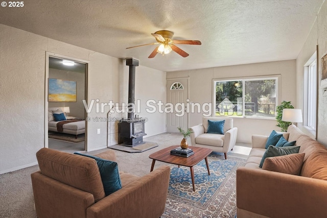 254 Humphrey Addition Rd, Glendale, OR 97442 - carpeted living room with a wood stove, a ceiling fan, a textured ceiling, a textured wall, and baseboards