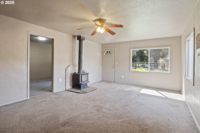 254 Humphrey Addition Rd, Glendale, OR 97442 - unfurnished living room with a wood stove, carpet floors, healthy amount of natural light, a textured ceiling, and a textured wall