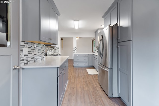10525 SE Mitchell St, Portland, OR 97266 - kitchen with stainless steel fridge, gray cabinetry, backsplash, light countertops, and light wood-type flooring