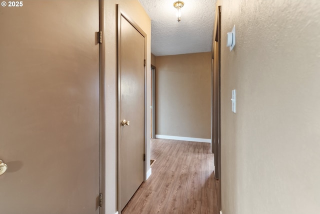 10525 SE Mitchell St, Portland, OR 97266 - hall with light wood-type flooring, a textured ceiling, and baseboards