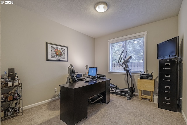 home office with a textured ceiling, baseboards, and light carpet