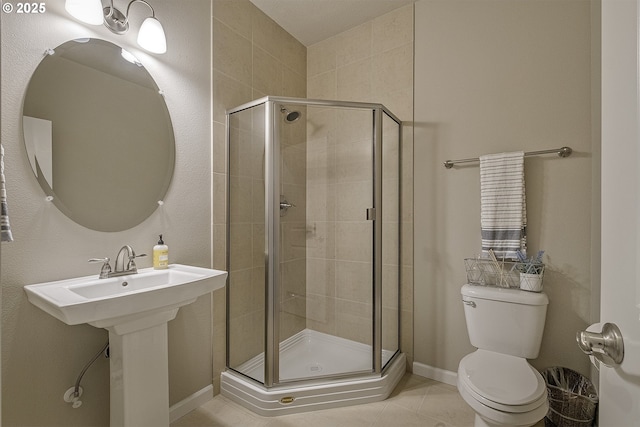 bathroom featuring tile patterned flooring, a shower stall, toilet, and a sink