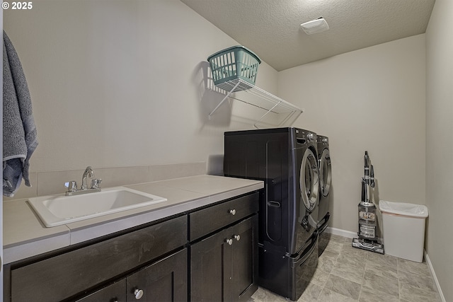 laundry room featuring baseboards, cabinet space, a textured ceiling, independent washer and dryer, and a sink