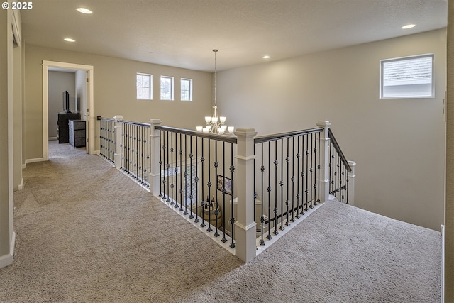 hallway featuring recessed lighting, carpet flooring, a healthy amount of sunlight, and an inviting chandelier