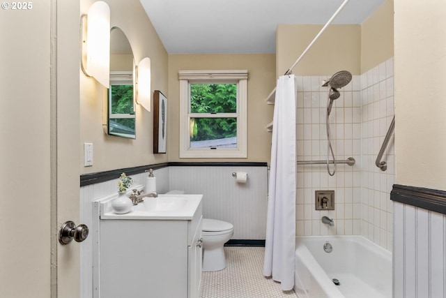 bathroom with a wainscoted wall, toilet, tile patterned flooring, shower / bathtub combination with curtain, and vanity