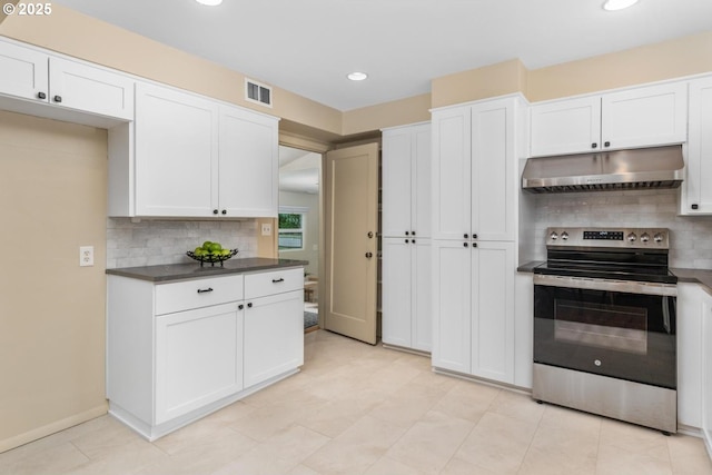 kitchen featuring electric range, under cabinet range hood, decorative backsplash, dark countertops, and recessed lighting