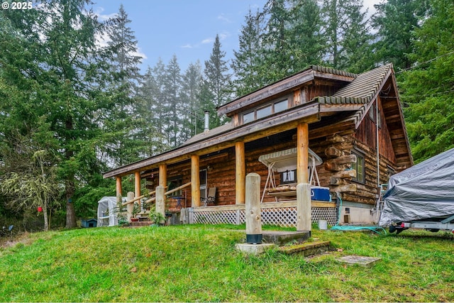 view of front facade featuring a front lawn, log exterior, and an outdoor structure