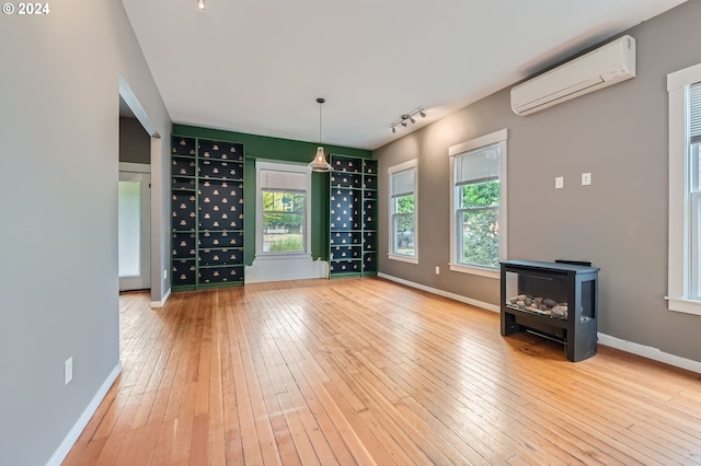 9116 N Willamette Blvd, Portland, OR 97203 - unfurnished living room with a wall unit AC, hardwood / wood-style flooring, rail lighting, and a wood stove
