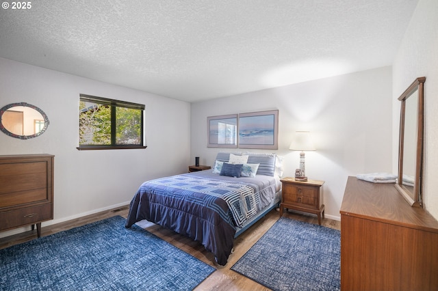 bedroom featuring wood finished floors, a textured ceiling, and baseboards