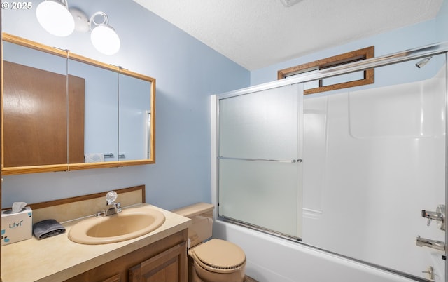 bathroom with combined bath / shower with glass door, vanity, toilet, and a textured ceiling