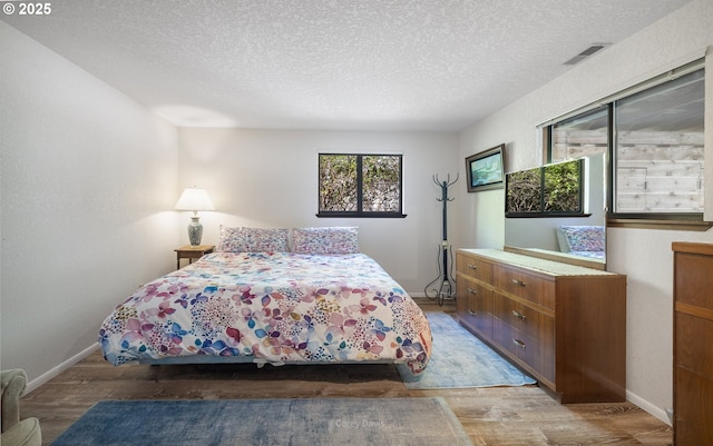 bedroom featuring wood finished floors, a textured ceiling, and baseboards