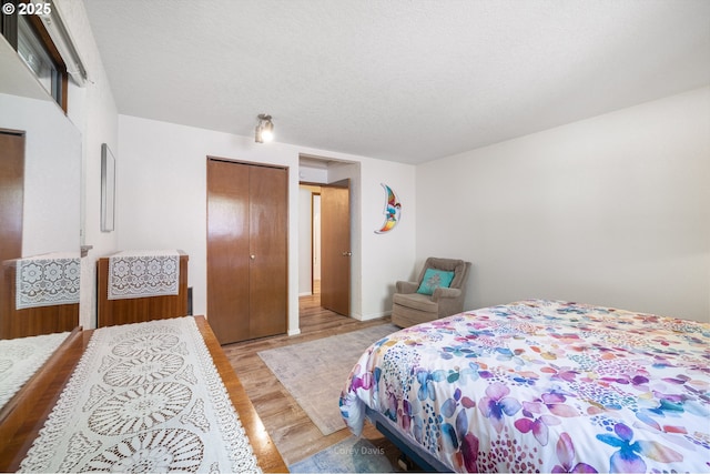 bedroom featuring light wood-type flooring, a closet, and a textured ceiling