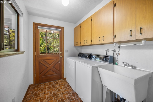 clothes washing area with cabinet space, brick patterned floors, and independent washer and dryer