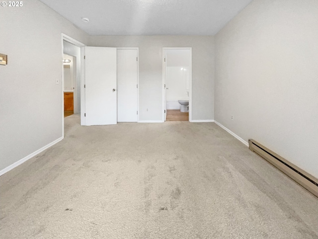 unfurnished bedroom featuring a baseboard heating unit, ensuite bath, and light colored carpet